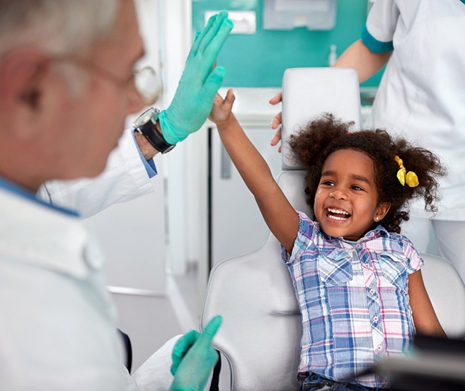 Happy little girl high-fiving her dentist